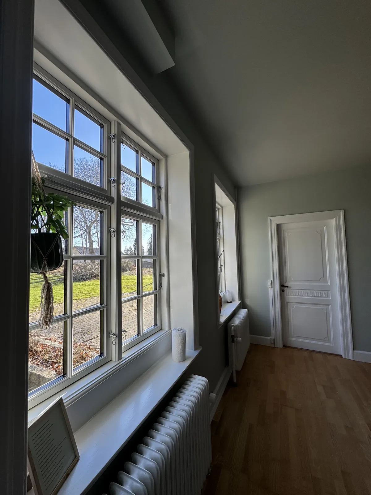 Lys gang med sprossede vinduer og grønne vægge